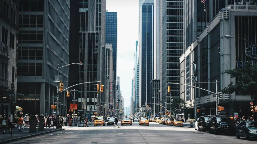 Taxis and traffic filling a city avenue between tall buildings.